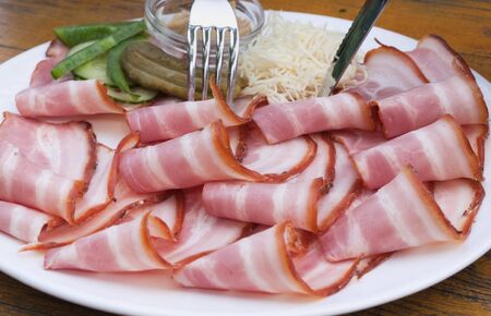 Pork bacon sliced thinly on a plateの写真素材