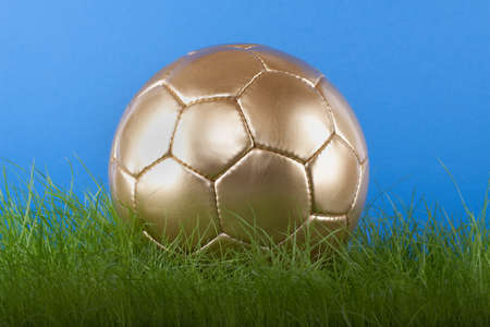 Gold soccer ball on grassの写真素材