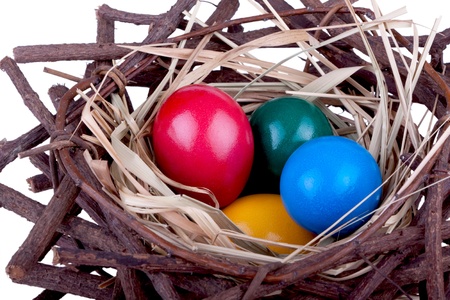 Colorful easter eggs in bird nest in front of white backgroundの写真素材