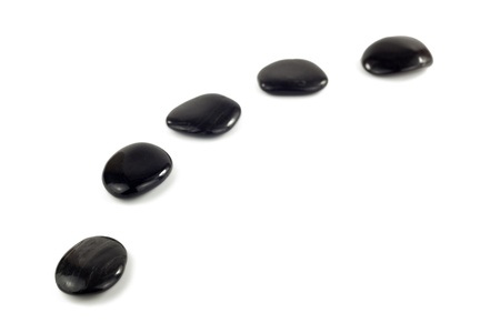 Black pebbles in a curved line in front of white backgroundの写真素材