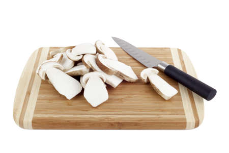 Sliced mushrooms on a chopping board with kitchen knifeの写真素材