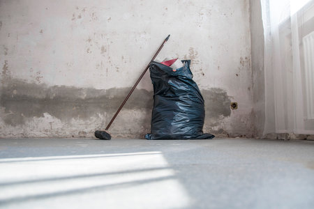 Renovation work: Broom and garbage bag with wallpaper garbage in front of a bare wallの写真素材
