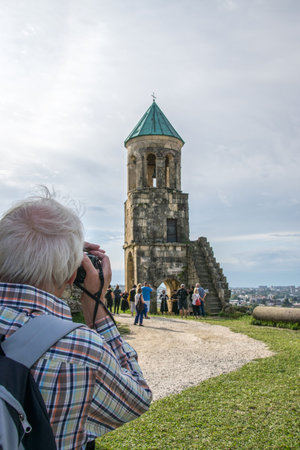 Looking over the shoulder of a photographer at a small chapel next to Bagrati Cathedral in Kutaisi,...