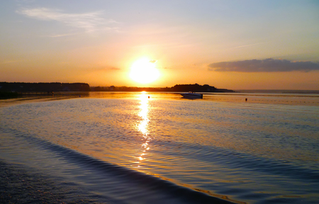 Small boat against the setting sun on the lake. Warm colors, sunsetの写真素材