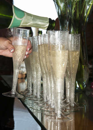 Don t mind if I do - a line of champagne glasses being filled as one is takenの写真素材