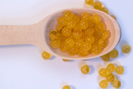 Fish oil. Cod liver oil omega 3 gel capsules. Granules in a wooden spoon on a white background.の写真素材