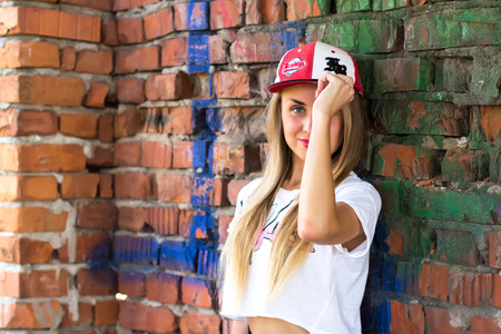 Pretty Girl in a baseball cap staying at brick wallの写真素材