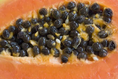 A papaya cut in half with the seeds in the centre