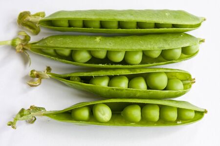 Fresh peas on three opened pods on a white background