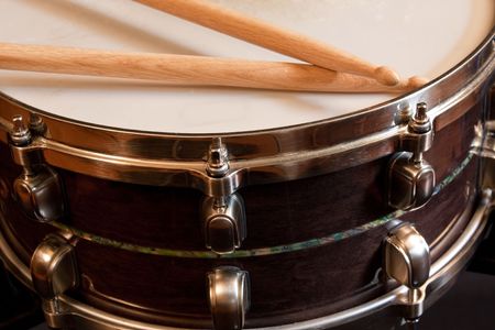 A snare drum with drumsticks resting on the skin