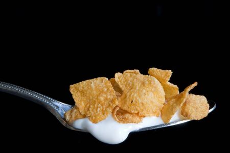 A spoonful of flaked corn cereal with milkの写真素材