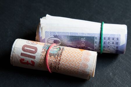 Rolls of ten pound and twenty pound notes secured with rubber bands