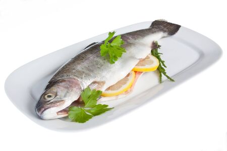 A rainbow trout prepared for cooking, stuffed with slices of lemon and parsleyの写真素材