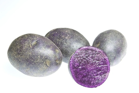 A selection of purple vitelotte potatoes isolated against a white backgroundの写真素材