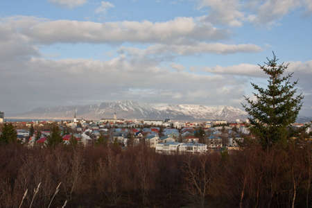 A view of Reykjavik, capital of Iceland, showing buildings, plants & the mountains behind the cityの写真素材