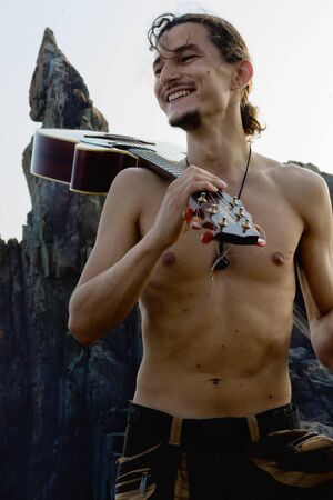 guitarman stay with guitar in front of the sky with rockの写真素材