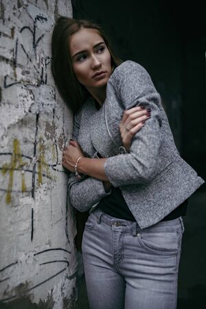 Girl in grey suit posing beside grey wallの写真素材