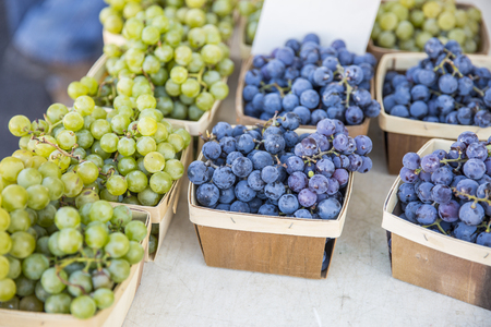 baskets of concord grapes on a table at a farmers market