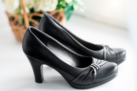Stylish summer classic woman's black leather shoes with medium heel on white background with flowers.の写真素材