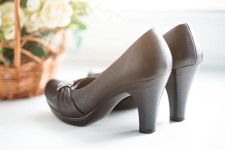 Beautiful classic vintage woman's black leather shoes with high heel on white background with flowers.の写真素材