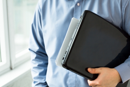 Businessman holding a laptop and working on itの写真素材