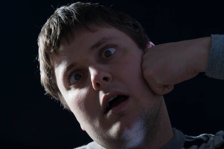 Businessman beat in the face with his fist on a black background