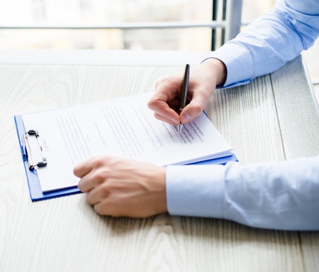 Business man hands signing on document at his deskの写真素材