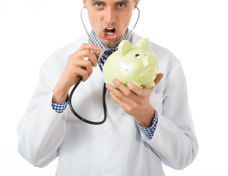 Female Doctor Holding Stethoscope to Pink Piggy Bankの写真素材