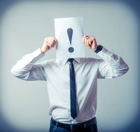 businessman holding exclamation mark on a gray backgroundの写真素材
