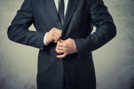 young business man button his jacket on a gray backgroundの写真素材