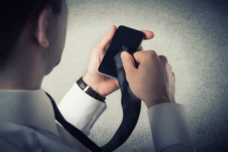 Close up of young businessman using smart phone on gray backgroundの写真素材