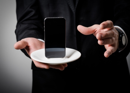 businessman holding a phone in his hand on a gray backgroundの写真素材