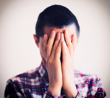 Desperate young man covering with his head in his handsの写真素材