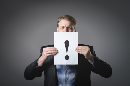 young businessman holding a sheet with exclamation mark on itの写真素材