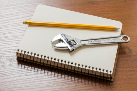 Notepad and Adjustable Wrench on the tableの写真素材