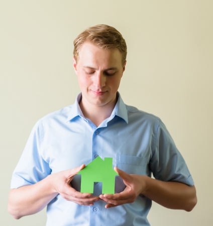 young man holding a paper house in handsの写真素材