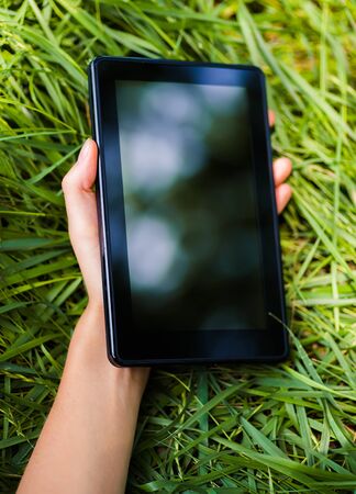 Young woman uses a digital tablet on the natureの写真素材