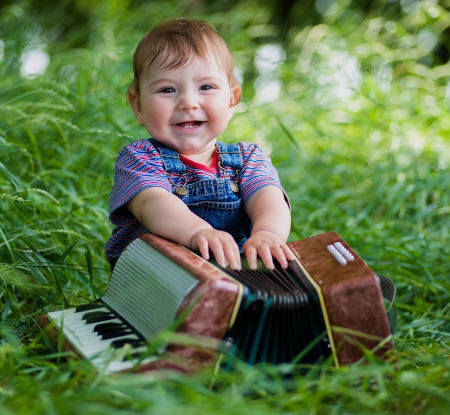 little boy playing with the accordionの写真素材