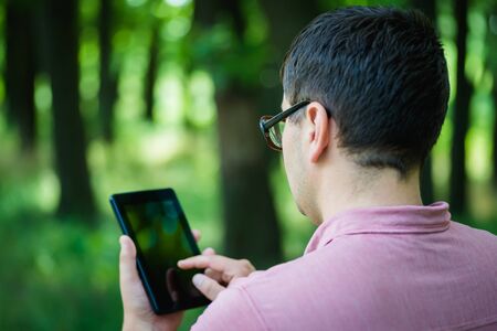 young man in glasses uses a digital tabletの写真素材