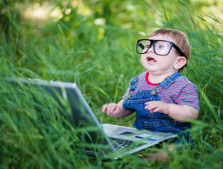 little boy playing outdoors with a laptopの写真素材