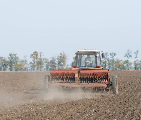 Farmer in tractor sowing crops at field with seed scattering agricultの写真素材