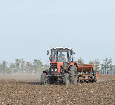 Farmer in tractor sowing crops at field with seed scattering agricultの写真素材
