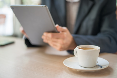 Man with tablet computer reading news at motning in cafeの写真素材