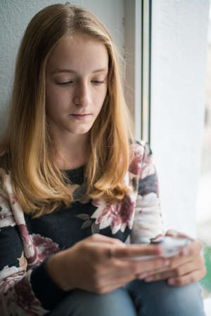 Young beautiful woman writes an SMS to your mobile phoneの写真素材