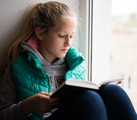 serious young, beautiful girl holding an open bookの写真素材