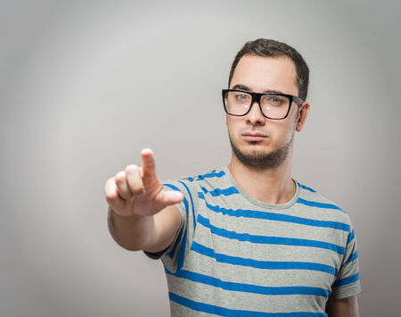 young man in glasses clicks index finger in the spaceの写真素材