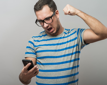 young man with glasses is angry at the phoneの写真素材