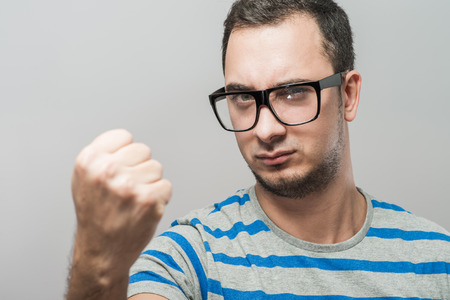 young man in glasses showing a fistの写真素材