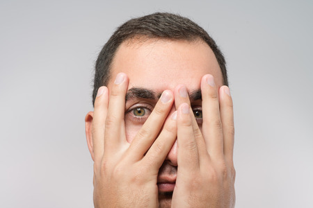 Young Caucasian man hiding his face with handの写真素材