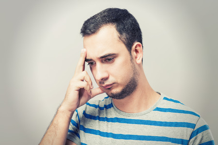 Depressed young man  holding head in handsの写真素材